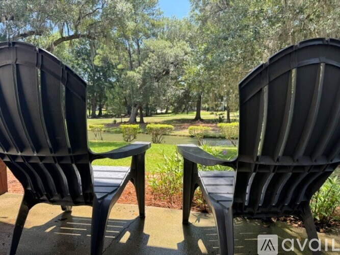 Two black chairs are placed on a concrete surface with trees in the background.