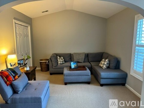 A living room with a grey couch and a blue ottoman.