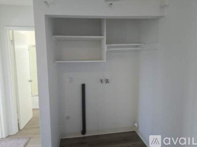A white wall with a shelf and a black pipe.
