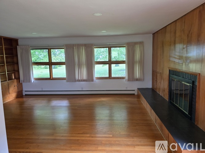 A spacious room with wooden floors and a fireplace.