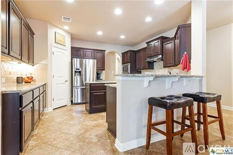 A kitchen with dark brown cabinets and a white counter.