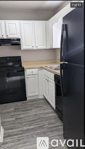 A kitchen with black appliances and white cabinets.