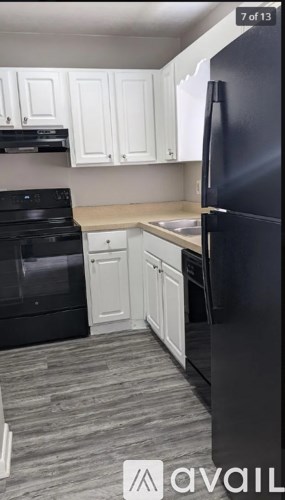 A kitchen with black appliances and white cabinets.