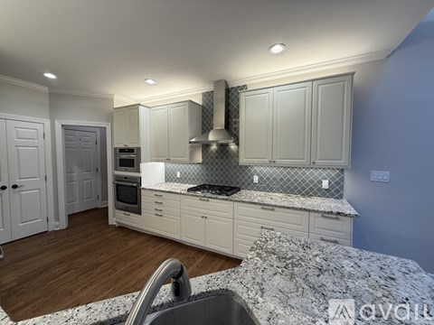 A modern kitchen with white cabinets and a wooden floor.