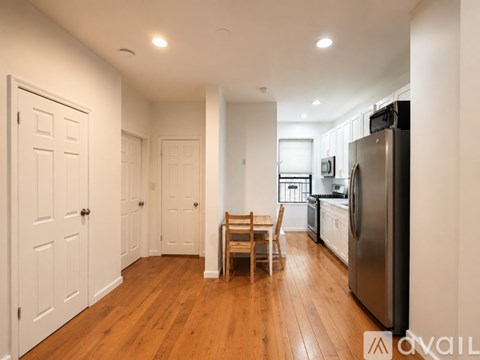 A kitchen with a refrigerator, sink, and a dining table with chairs.