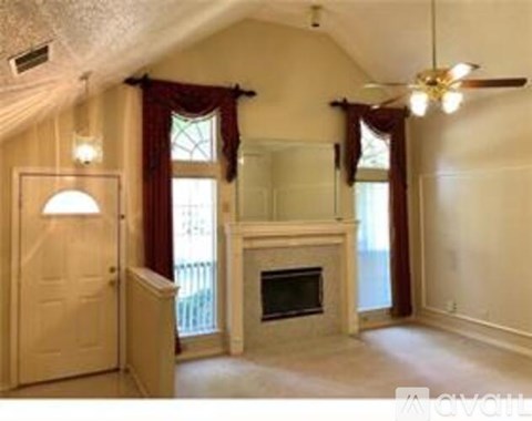 A living room with a fireplace and a ceiling fan.