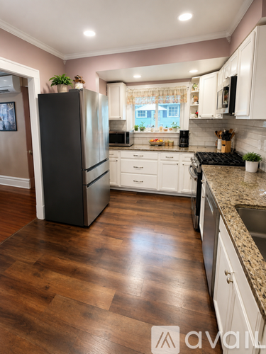 A kitchen with a black fridge and wooden floors.