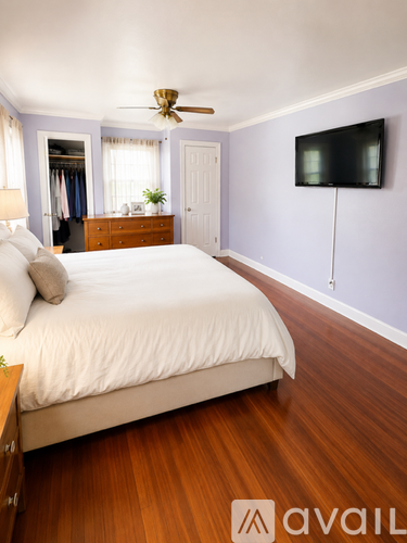 A bedroom with a bed, dresser, and a ceiling fan.