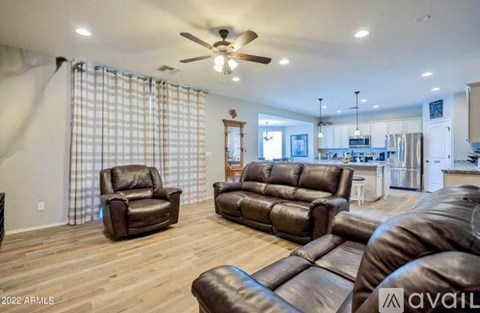 A living room with brown leather furniture and a ceiling fan.