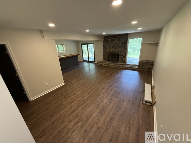 A spacious living room with wood flooring and a stone fireplace.