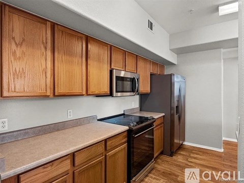 A kitchen with wooden cabinets and a black refrigerator.