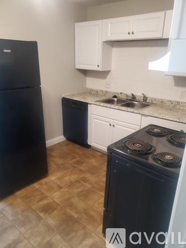 A black fridge and stove in a kitchen with white cabinets.