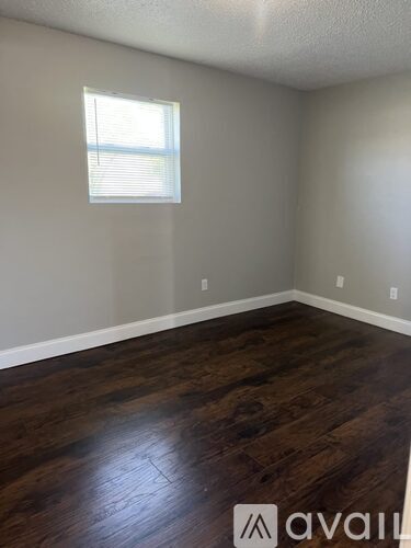 A room with wooden flooring and a window with blinds.