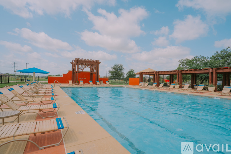 A large outdoor swimming pool with sun loungers and a wooden structure.