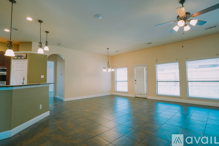 A spacious room with a ceiling fan and pendant lights.