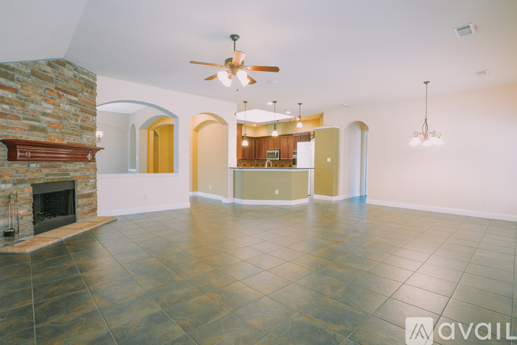 A spacious living room with a stone fireplace and a ceiling fan.