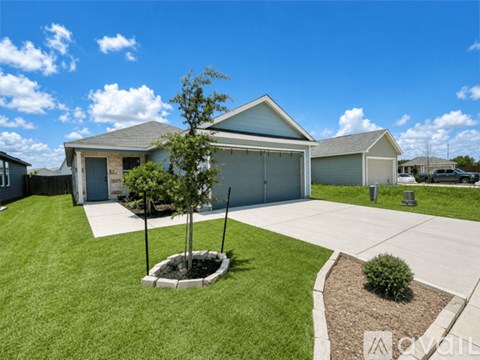 A house with a garage and a tree in the front yard.