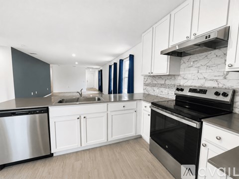 A modern kitchen with white cabinets and stainless steel appliances.