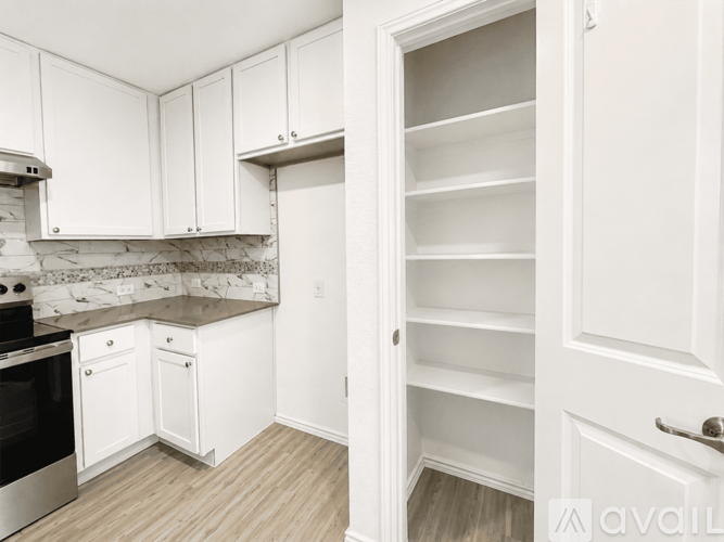 A kitchen with white cabinets and a marble backsplash.