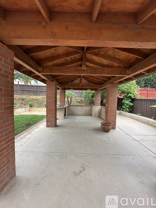 A wooden covered walkway with a brick pillar and a concrete floor.