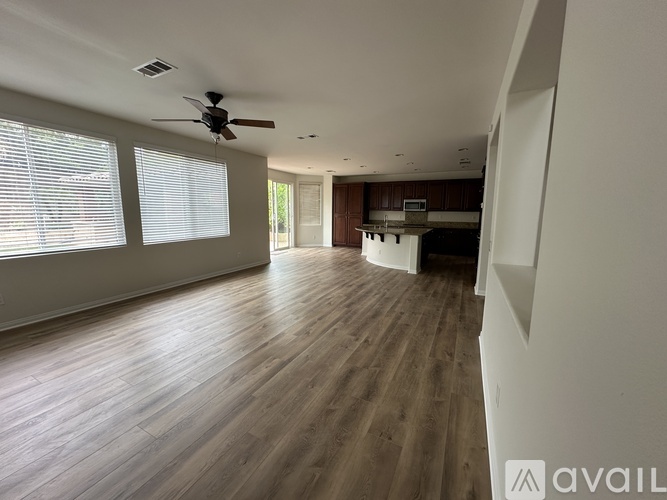 A spacious room with wooden flooring and a ceiling fan.