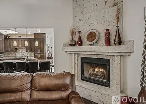 A living room with a brown leather couch and a fireplace.