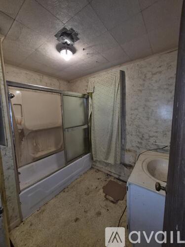 A dirty bathroom with a toilet, sink, and shower.