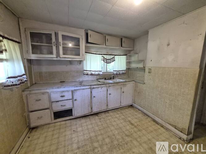 A kitchen with white cabinets and a checkered floor.