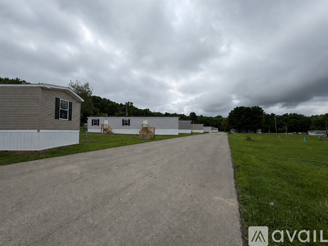 A cloudy sky over a residential area with houses and a grassy field.