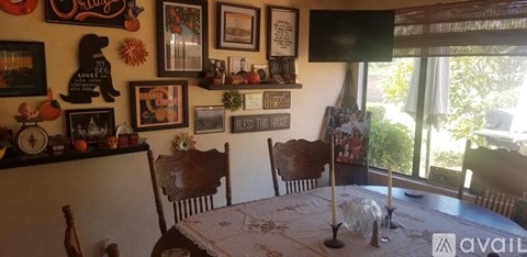 A dining room with a table set for four and a wall of pictures and decorations.