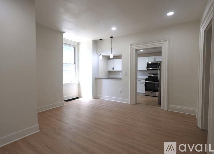 A spacious room with wooden floors and white walls.