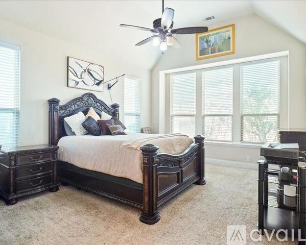 A bedroom with a large bed and a ceiling fan.