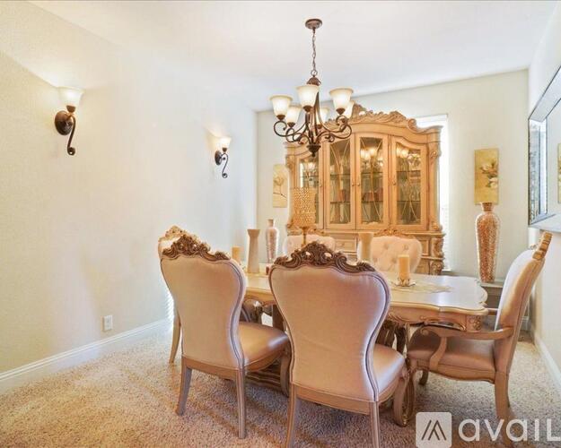 A dining room with a chandelier, four chairs, and a table.
