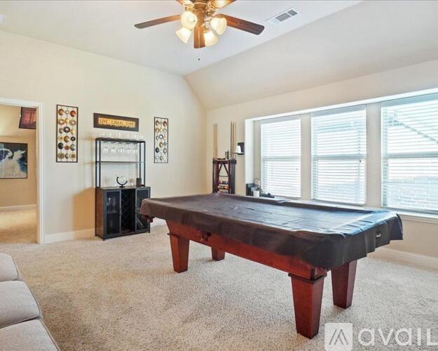 A room with a pool table and a ceiling fan.
