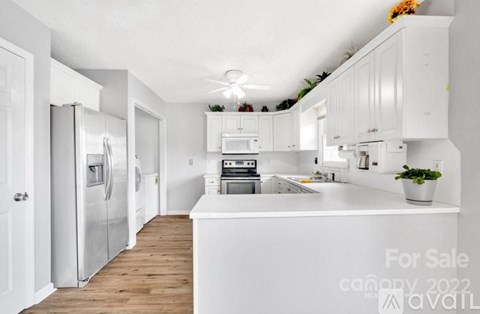 A kitchen with white cabinets and appliances is for sale.