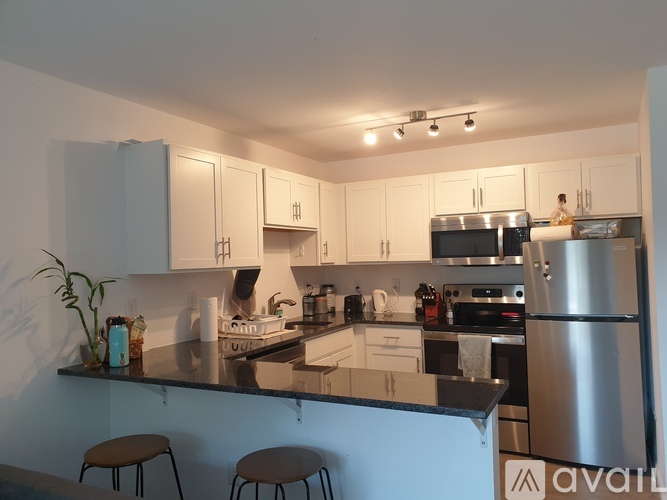 A kitchen with a black counter top and stainless steel appliances.