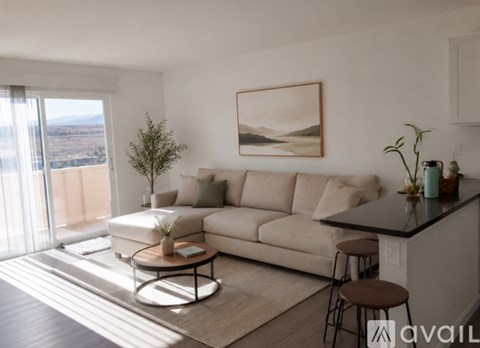 A living room with a beige couch, a coffee table, and a painting on the wall.