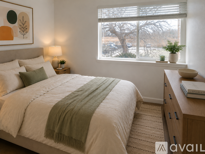 A bedroom with a large bed and a window overlooking a tree.