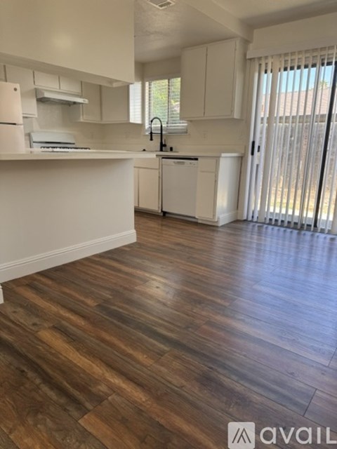 A kitchen with white cabinets and a wooden floor.