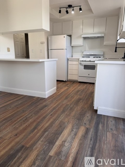 A kitchen with white appliances and wooden floors.
