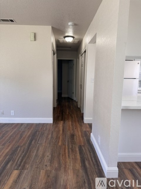 A long hallway with wood floors and white walls.