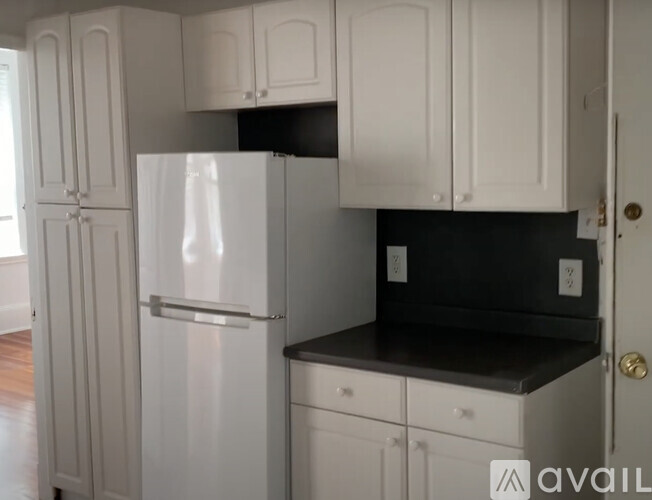 A kitchen with white cabinets and a black countertop.