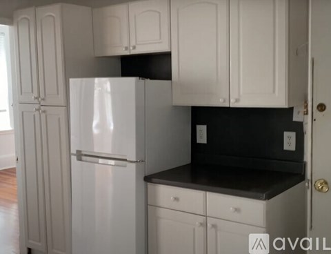 A kitchen with white cabinets and a black countertop.
