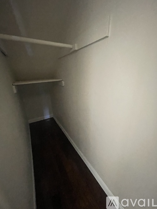 A long hallway with a white wall and a wooden floor.