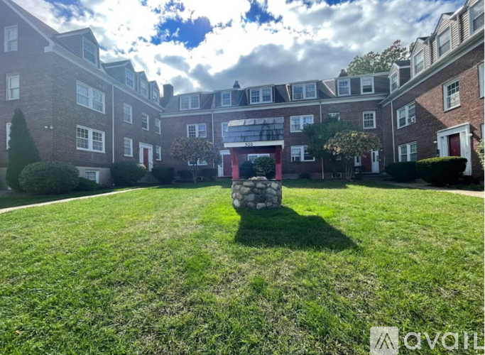 A grassy area in front of a building with a stone structure in the middle.