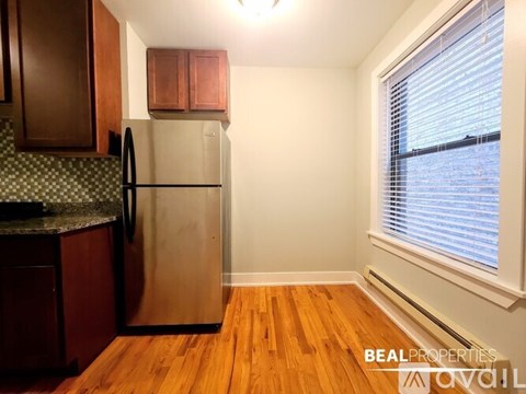 A kitchen with a refrigerator, cabinets, and a window.
