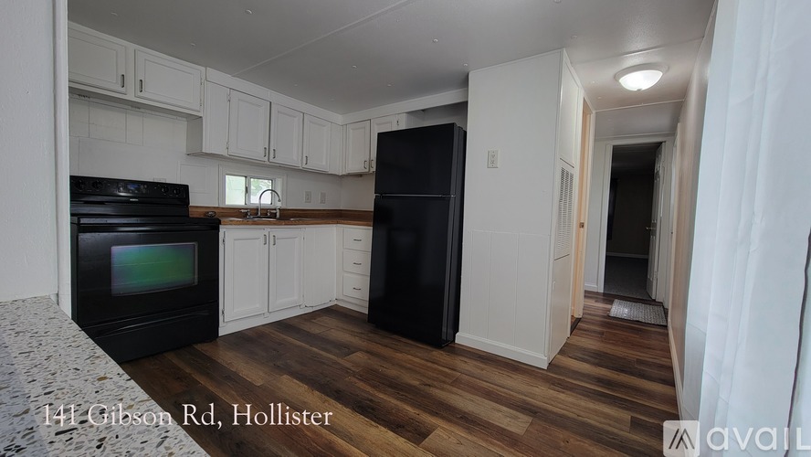 A kitchen with black appliances and white cabinets at 141 Gibson Rd, Hollister.