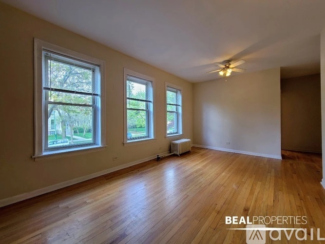 A room with wooden floors and three windows is available for rent.