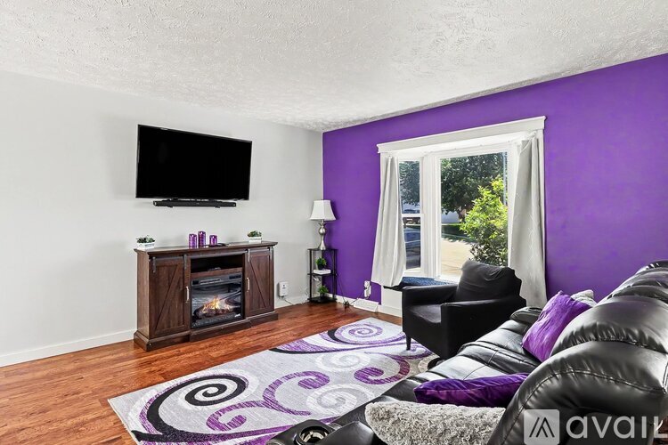 A living room with purple walls and a television.