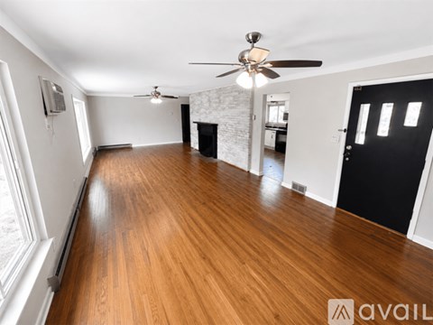 A spacious room with wooden floors and a ceiling fan.